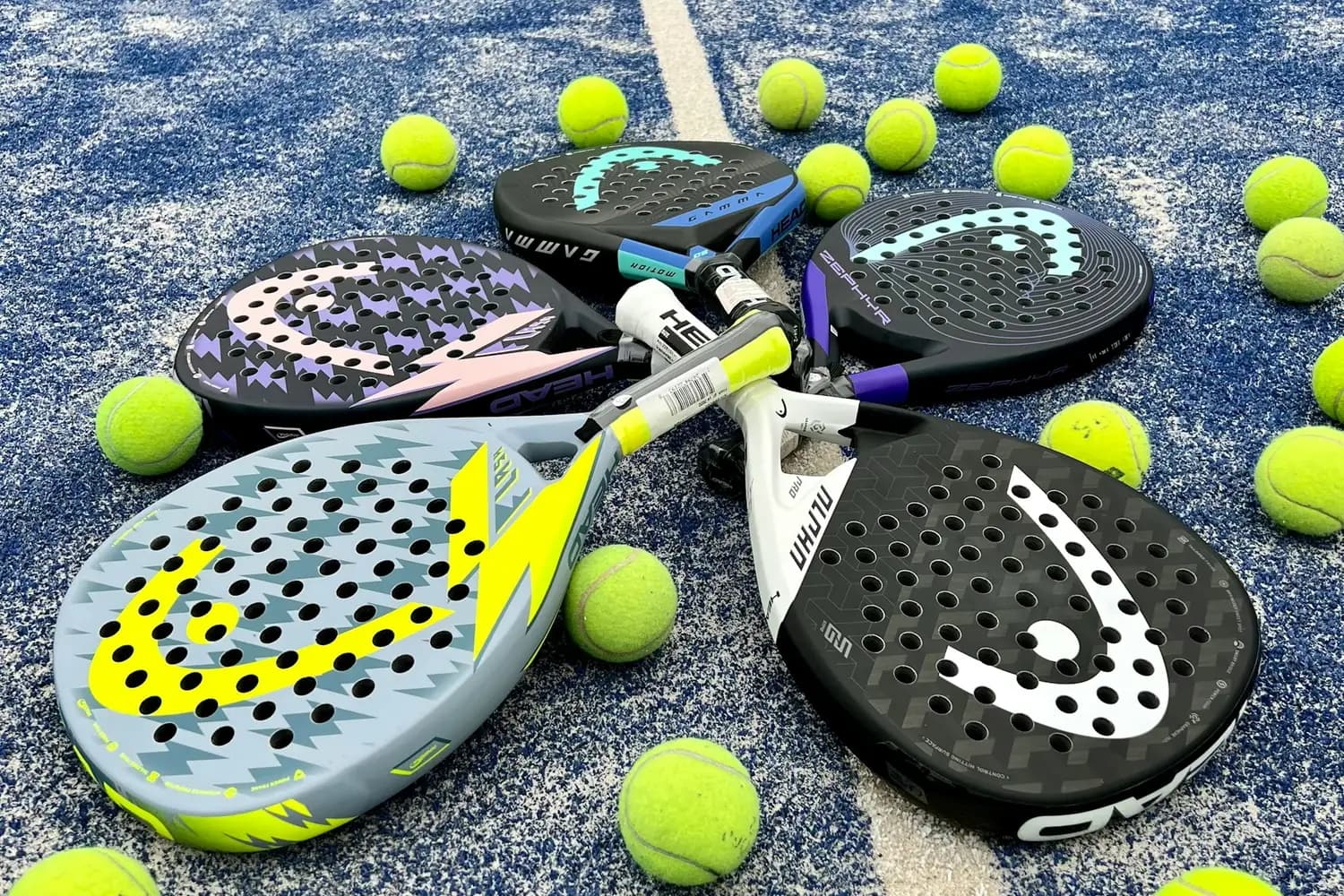 Padel rackets and yellow balls on a blue court surface