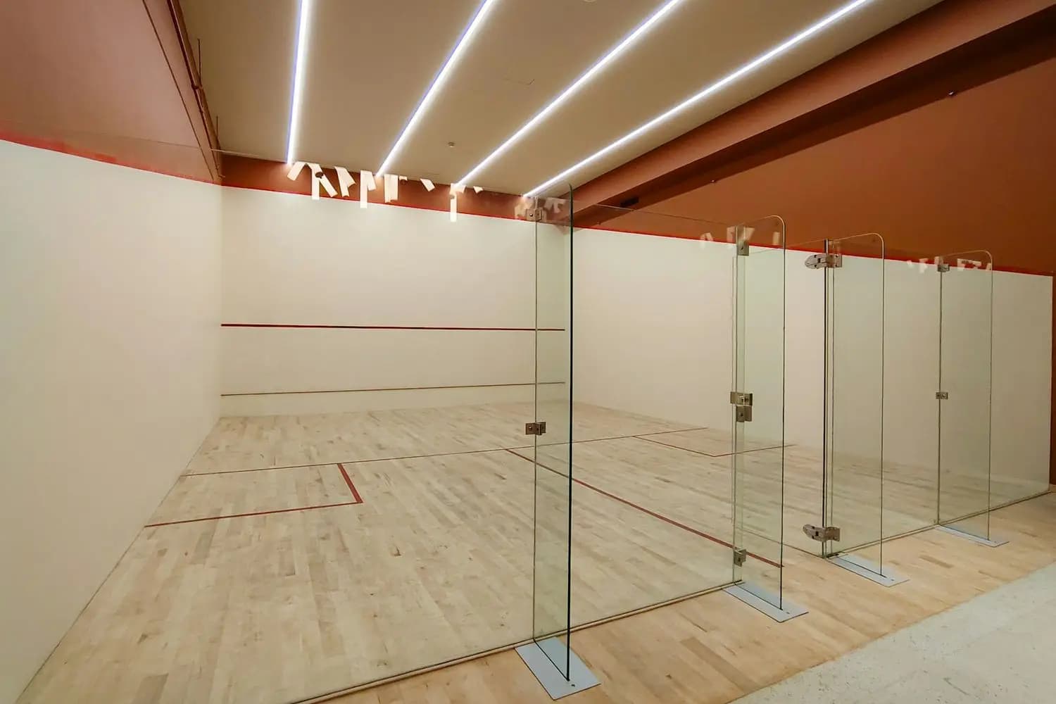 An empty squash court with a glass back wall